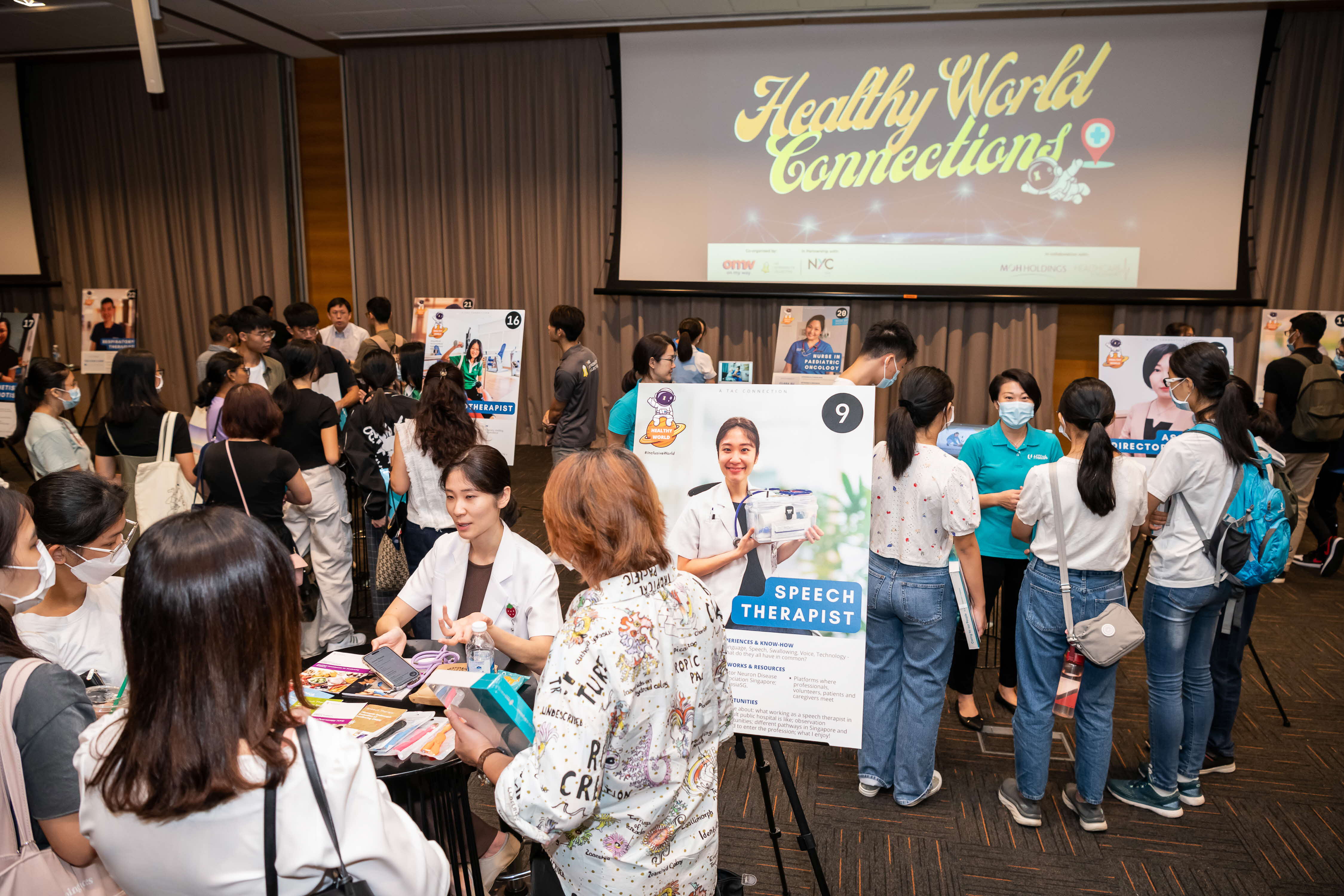 Indoor job fair with attendees looking at booths advertising healthcare careers.